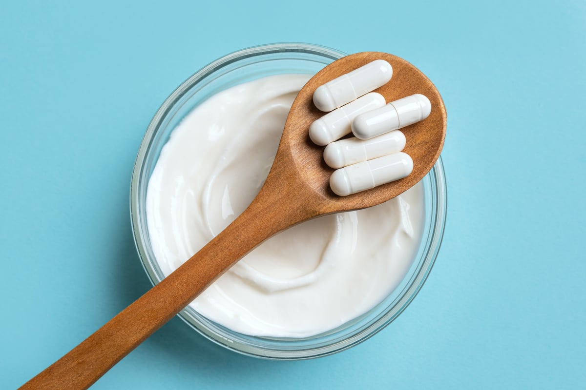 Probiotic capsules on wooden spoon with fermented foods for gut health
