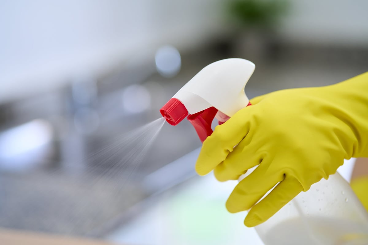 Gloves, cleaning and hand with disinfectant spray for housekeeping, bacteria removal or housework. Hygiene, person and chemical bottle in home for domestic chores, germ protection or virus sanitation at home.
